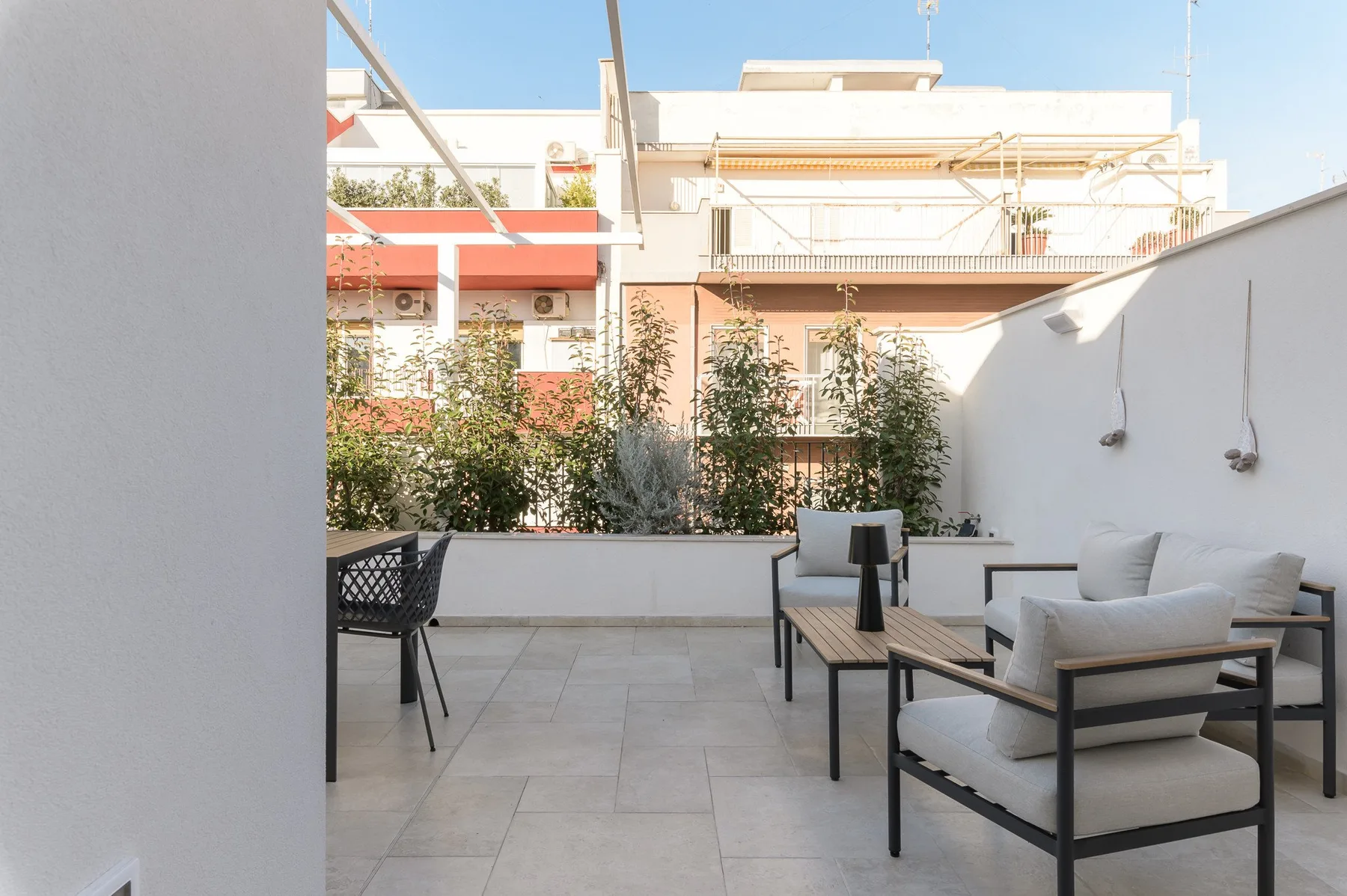 Un patio exterior con asientos acolchados y una mesa baja.