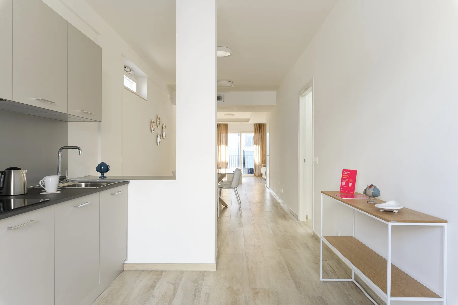 Una cocina luminosa da a un pasillo, con una consola estrecha junto a la pared.