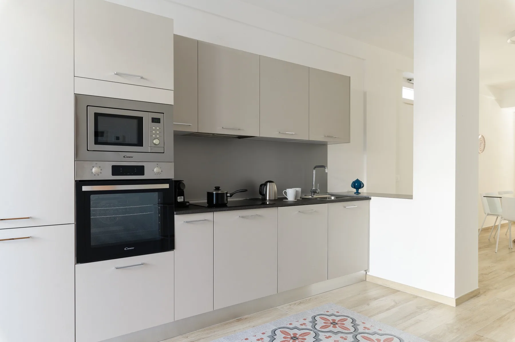 Una cocina moderna con gabinetes claros, electrodomésticos empotrados y una encimera oscura.