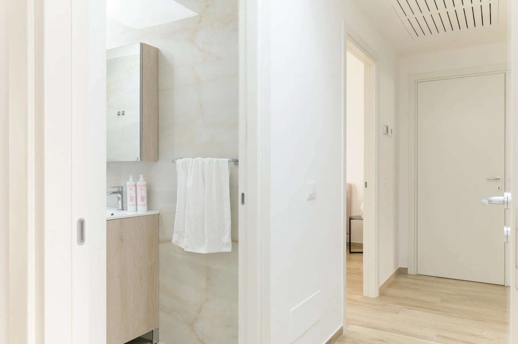 Un baño luminoso con un mueble de lavabo y una toalla colgada al lado.