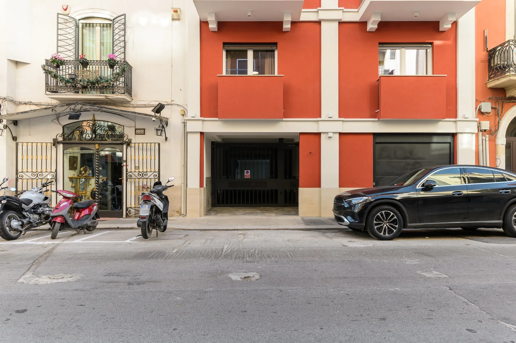 Un edificio de apartamentos rojo da a una calle de la ciudad, con vehículos estacionados delante.