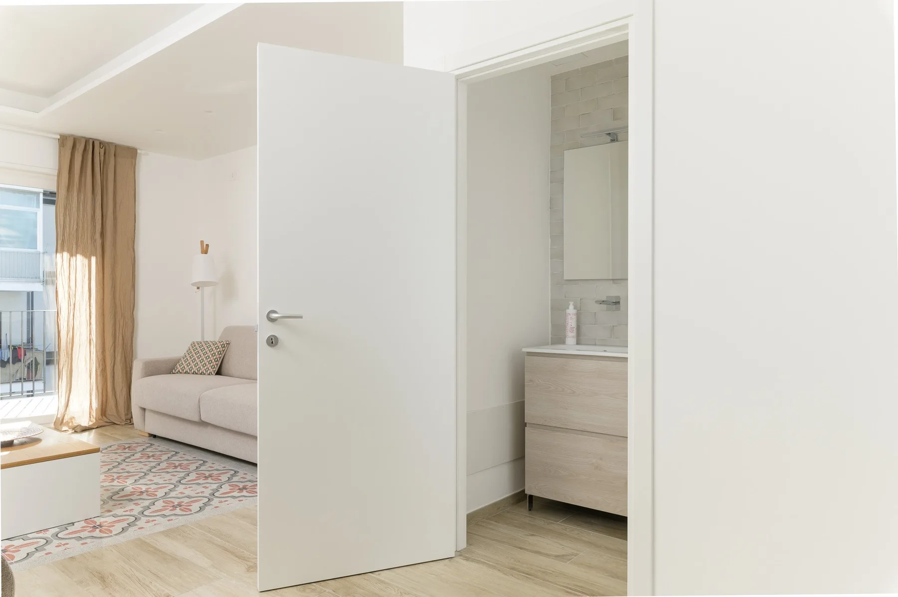 Se ve una sala luminosa junto a la entrada abierta de un baño.