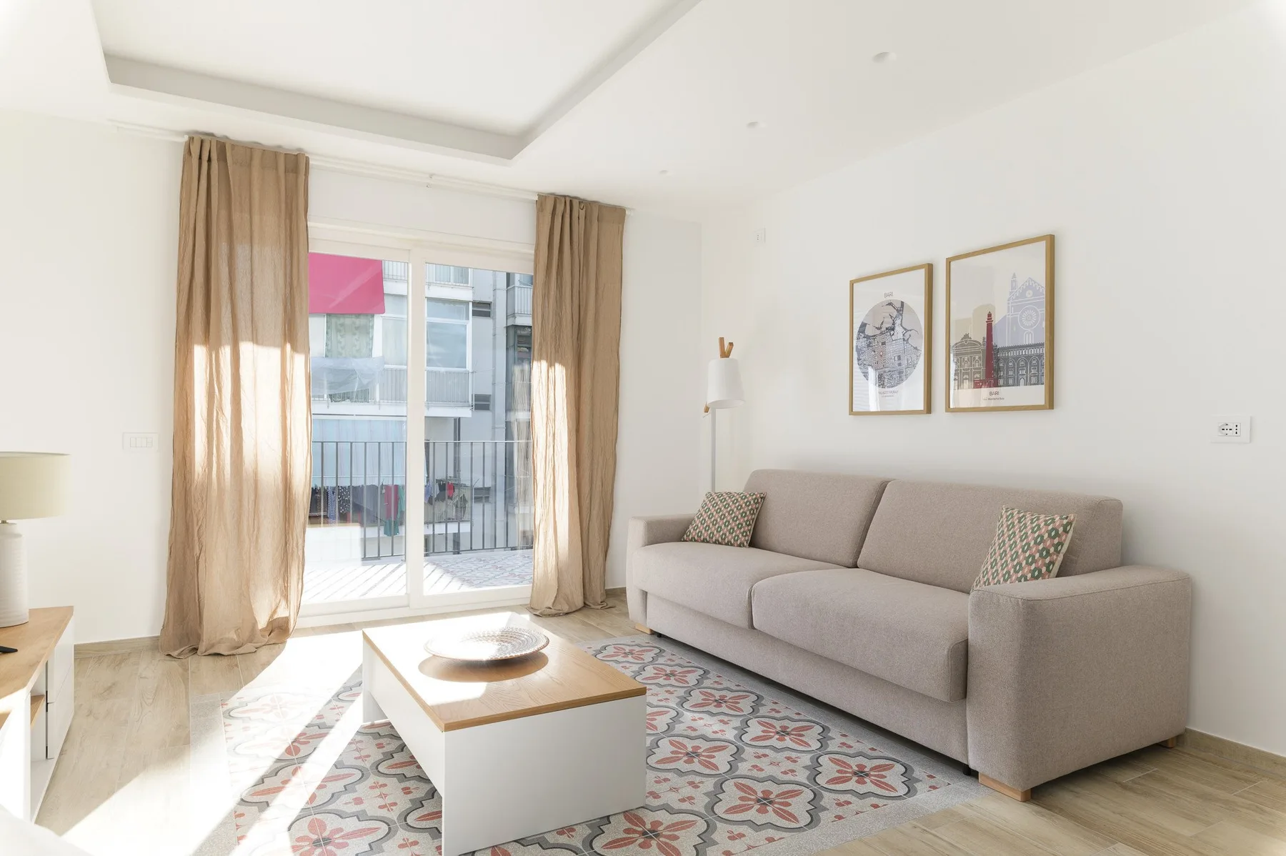 Una sala luminosa con sofá, mesa de centro y puertas de vidrio que dan a un balcón.