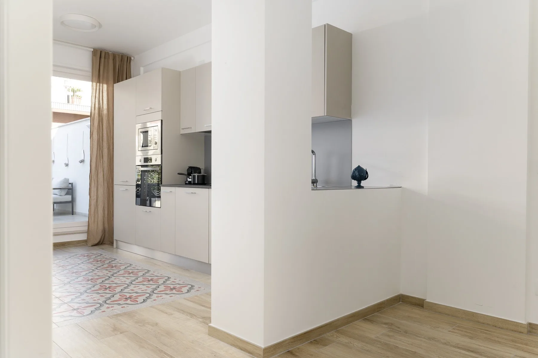 Una cocina luminosa con electrodomésticos integrados y una alfombra estampada.