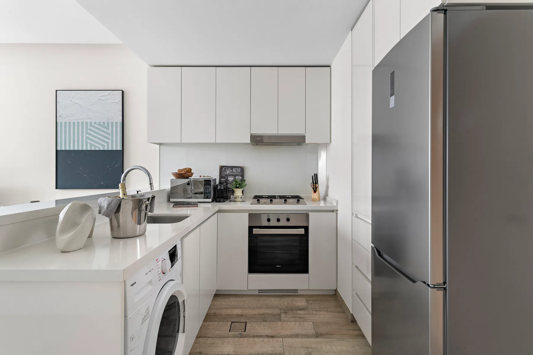 A compact modern kitchen with white cabinets, a countertop, and stainless steel appliances.