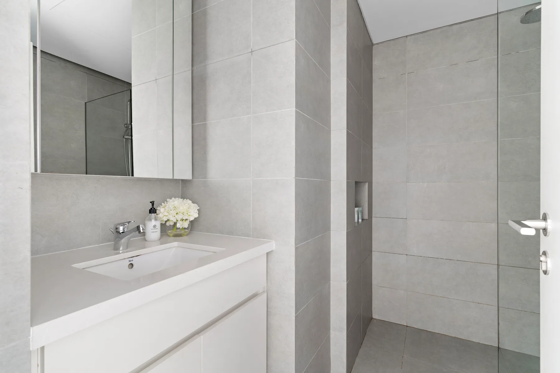 A modern bathroom with a sink vanity and tiled shower area.