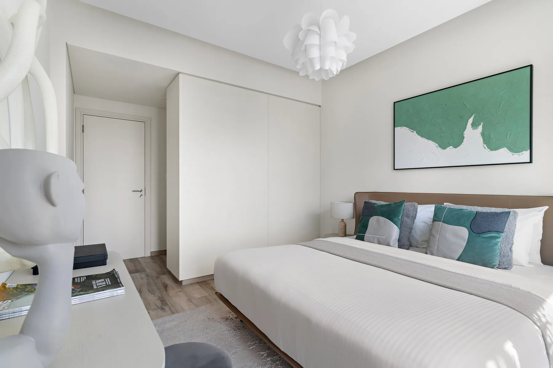 A bright bedroom with a large bed and green artwork above the headboard.