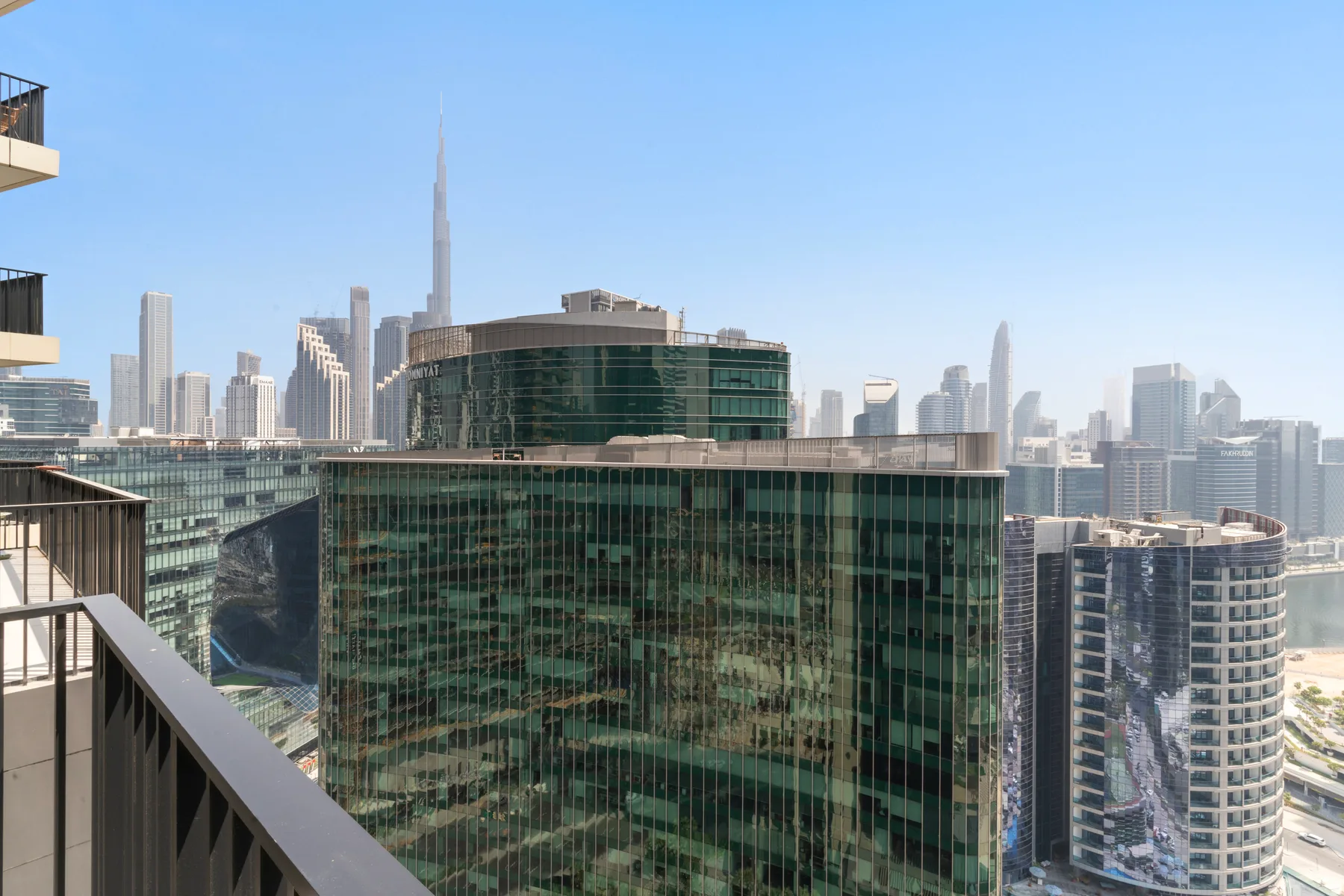 A city skyline of modern high-rise buildings under a clear blue sky.