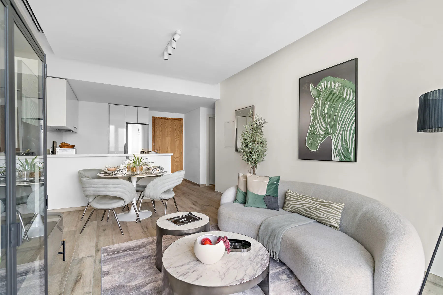 A living room with curved seating, round tables, and framed wall art.