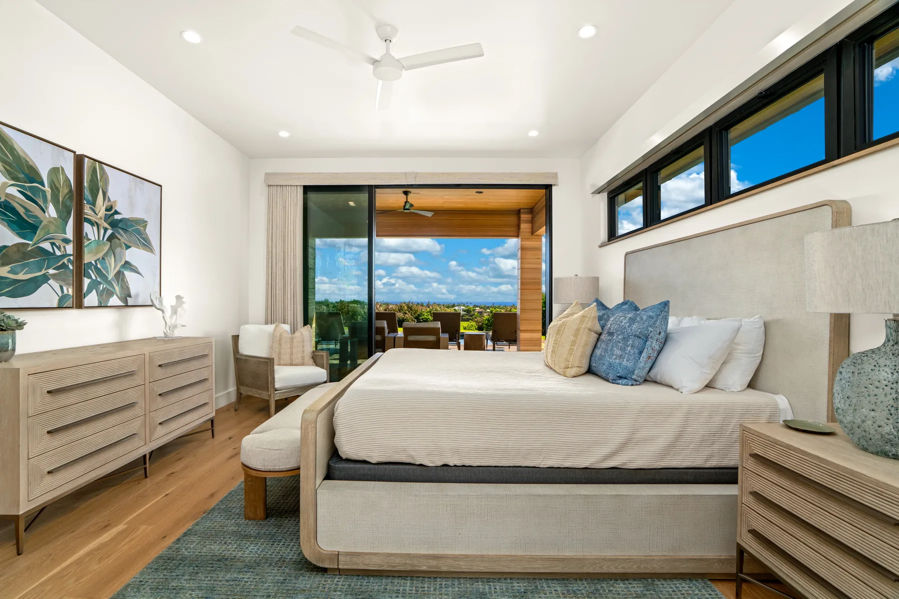 A bright bedroom with a large bed, bedside tables, and wide windows.