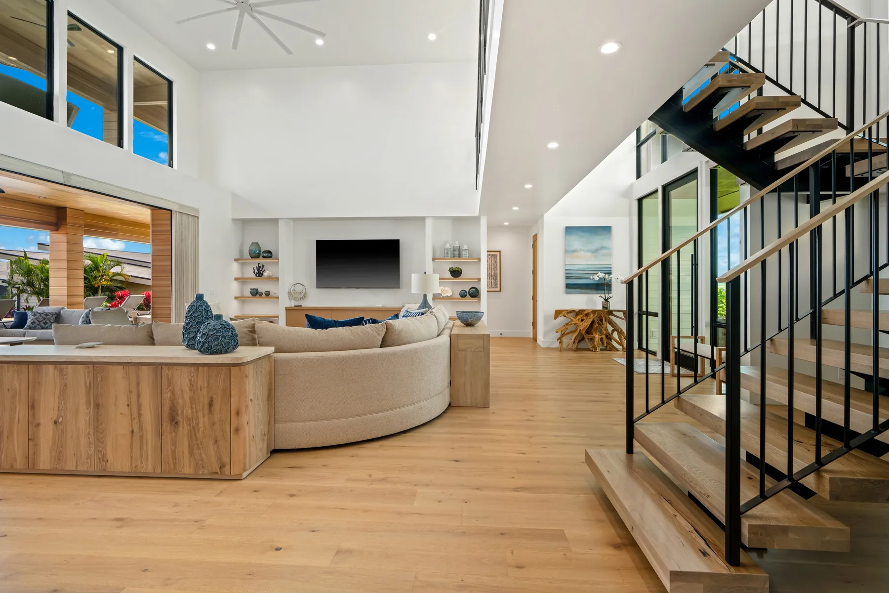 A bright open-plan living room with a curved seating area and staircase.