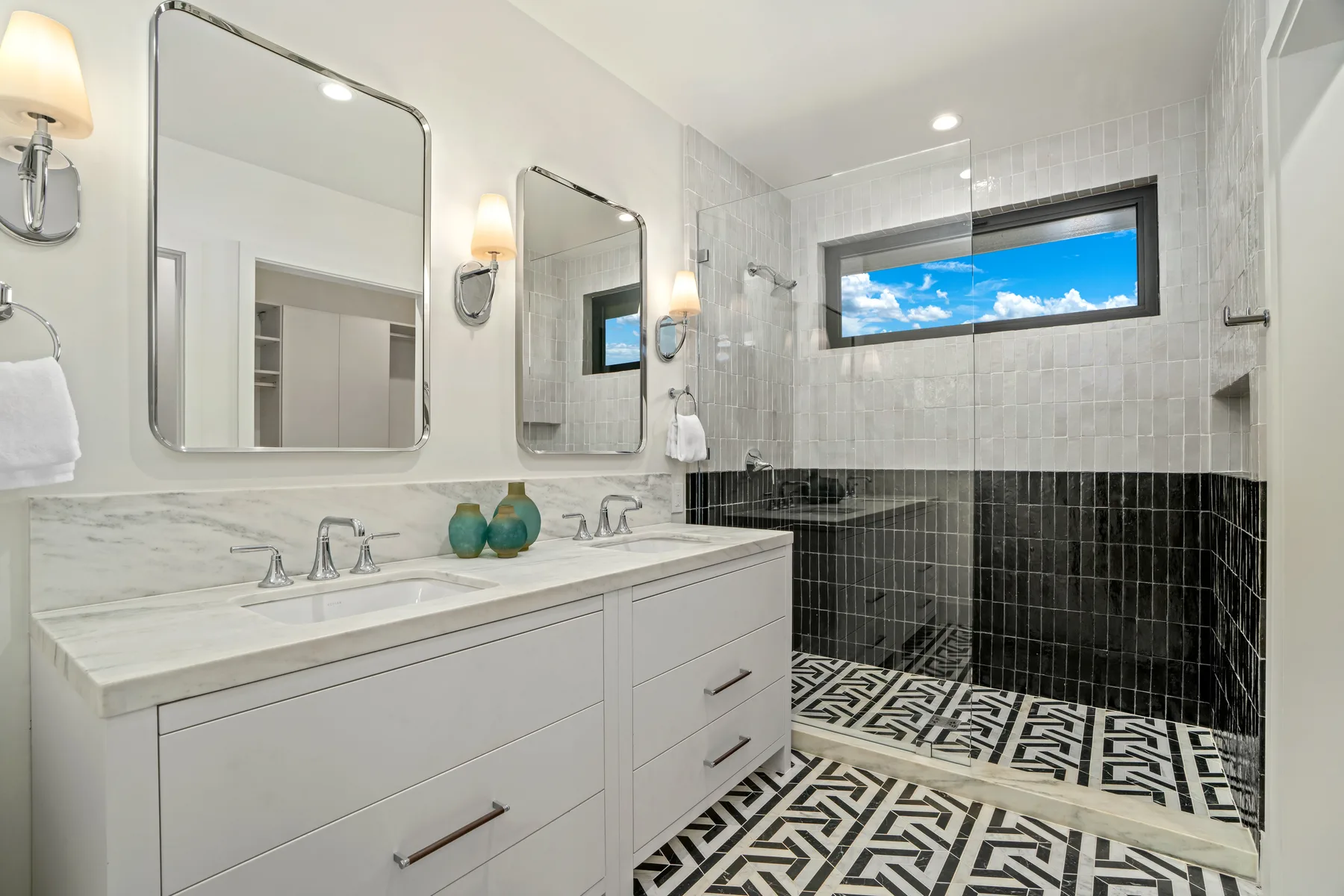 A tiled bathroom with a double vanity and a patterned floor.