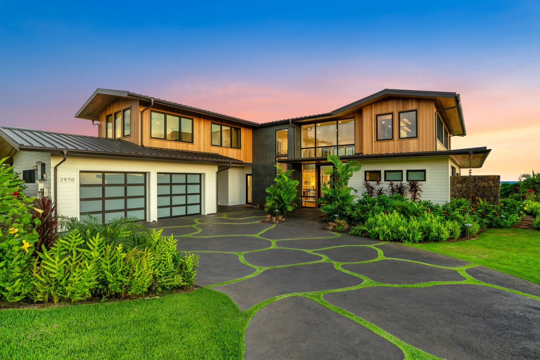 A modern two-story house with a broad driveway and landscaped garden.