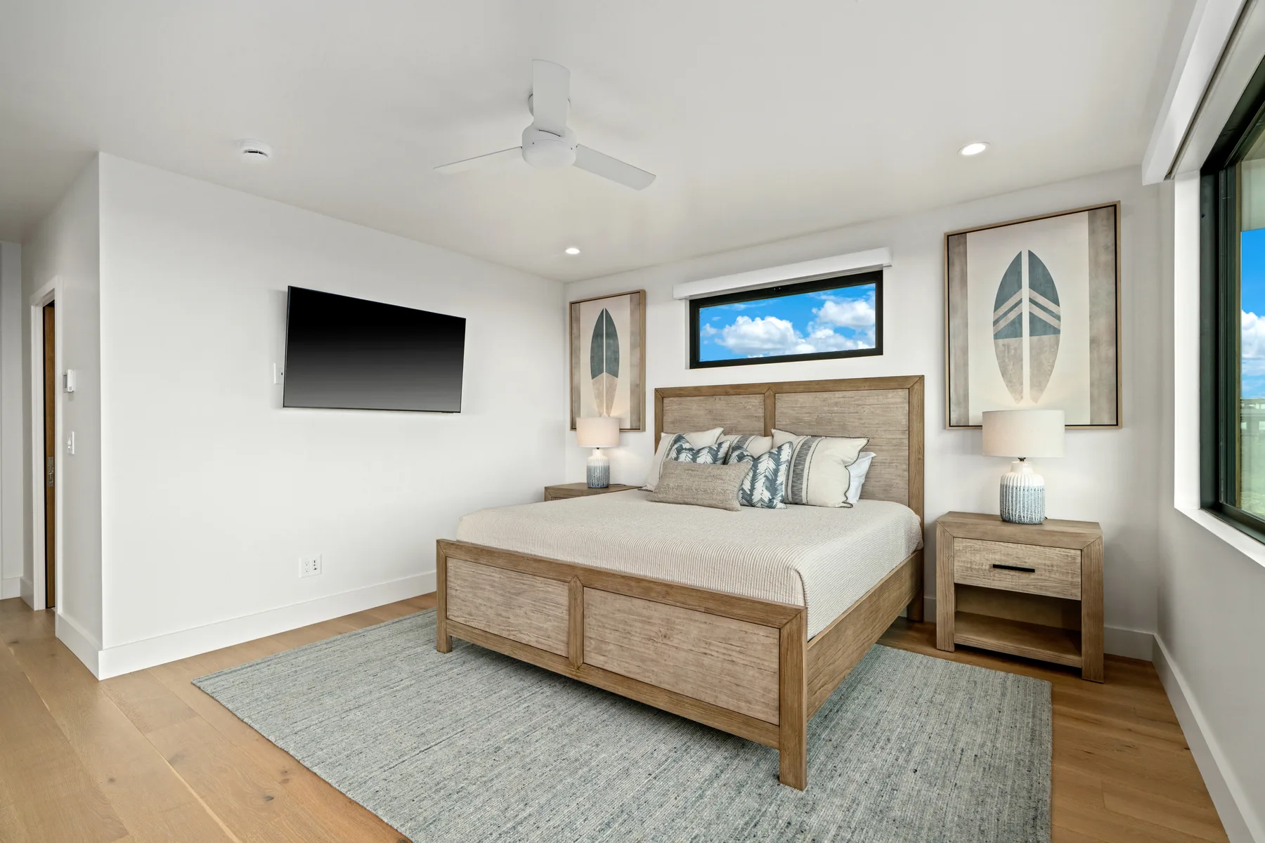 A bright bedroom with a bed, matching bedside tables, and a wall-mounted television.