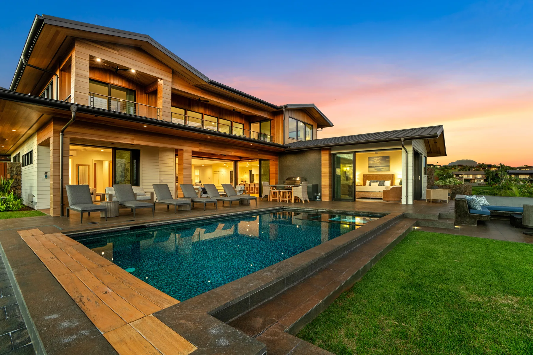 Modern house with a swimming pool and outdoor seating at sunset.