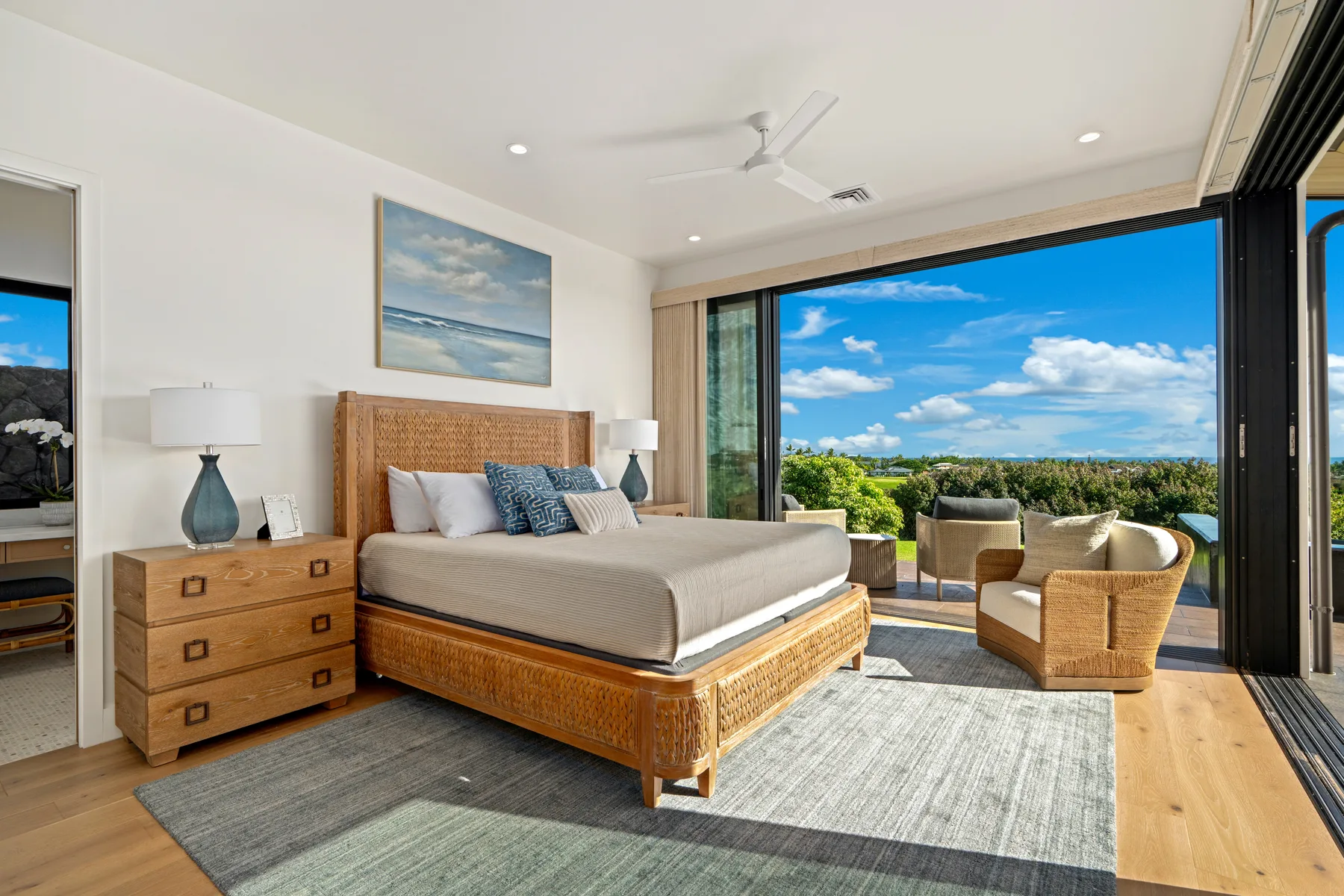 A bright bedroom opens onto a balcony, with a bed and outdoor seating.