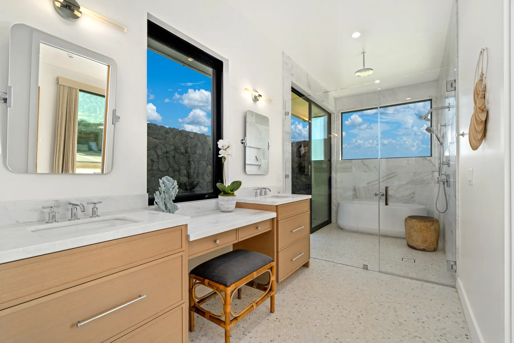 A bright bathroom with a long vanity and a glass-enclosed shower.