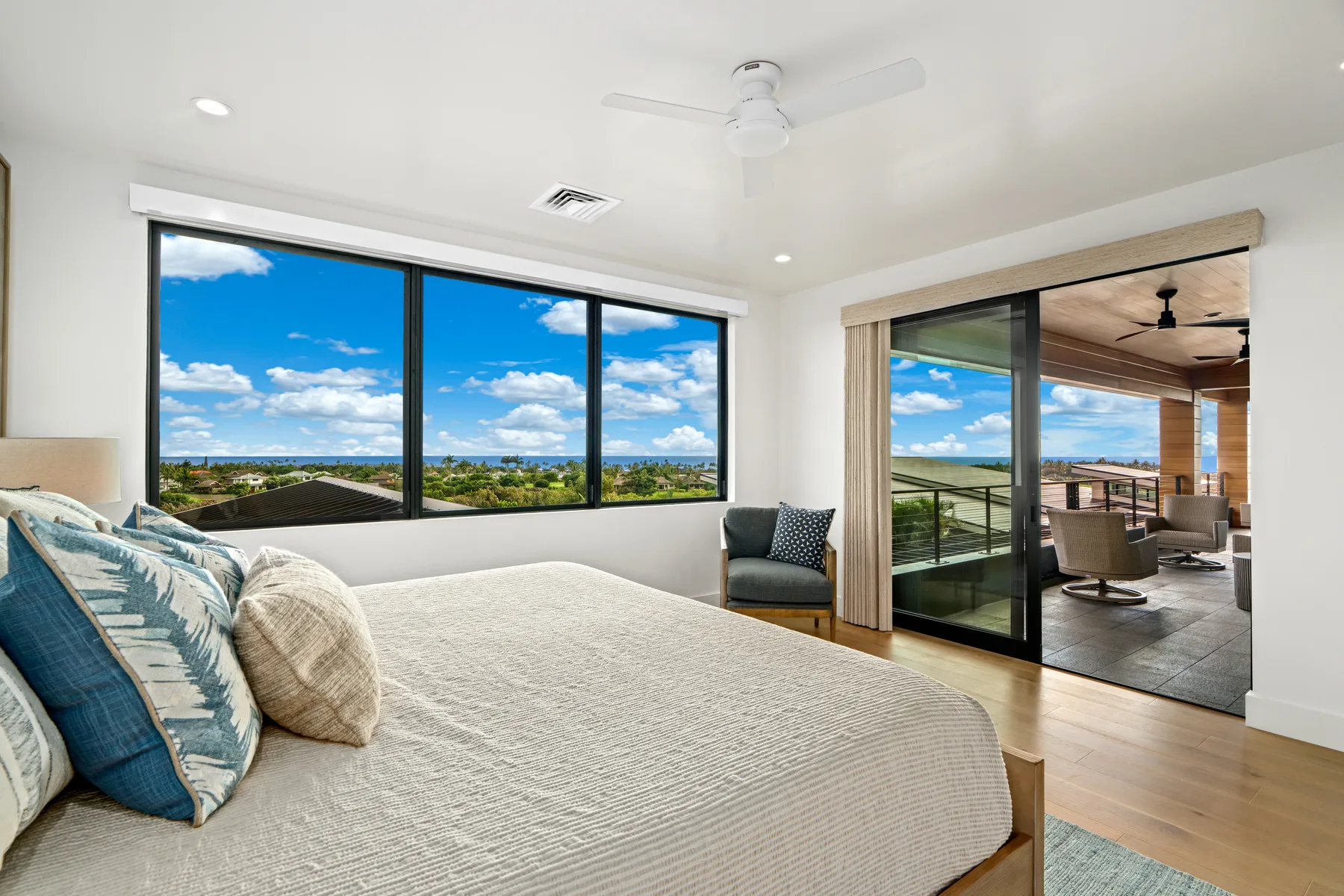 A bright bedroom opens onto a covered patio through large sliding glass doors.