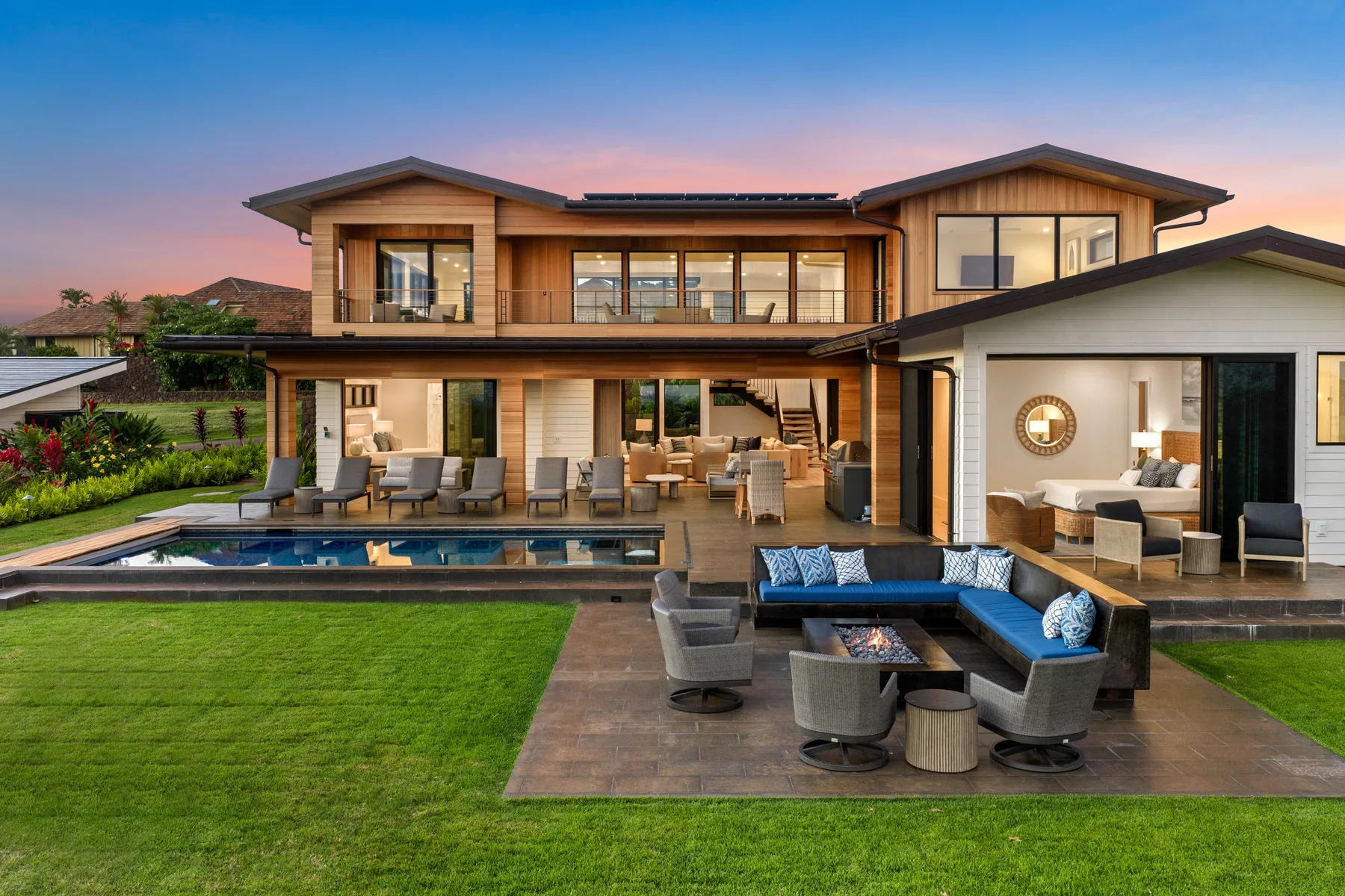 A modern house opens onto a landscaped patio with a pool and outdoor seating.