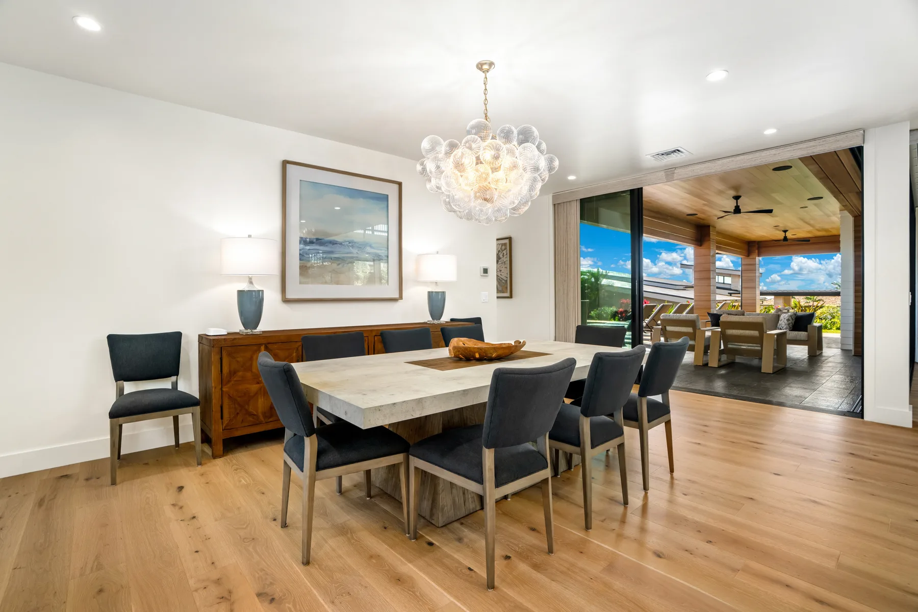 A dining room with a long table and an open view into a covered patio.