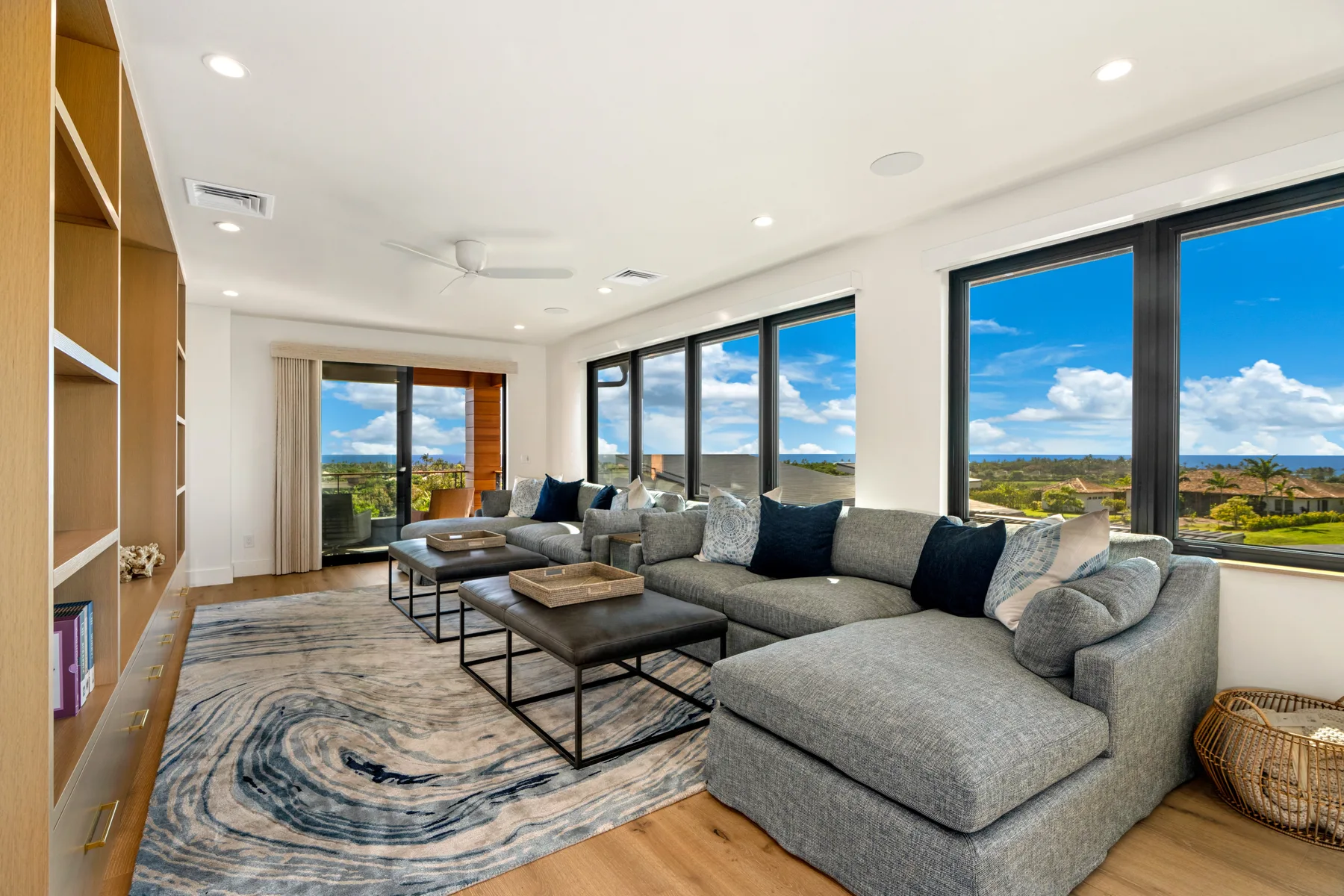 A bright living room with sectional seating beside large windows overlooking the landscape.