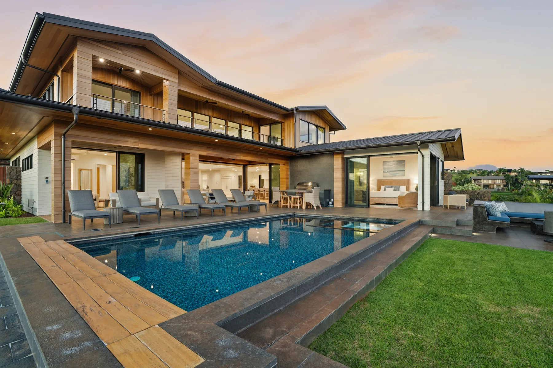 A modern house with a swimming pool and outdoor seating at dusk.