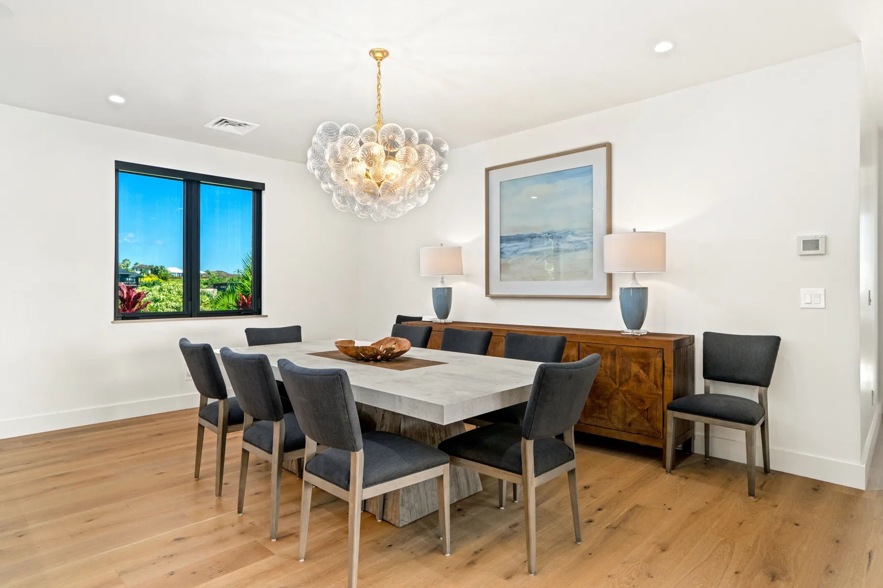 A dining room with a large table, dark seating, and a chandelier.