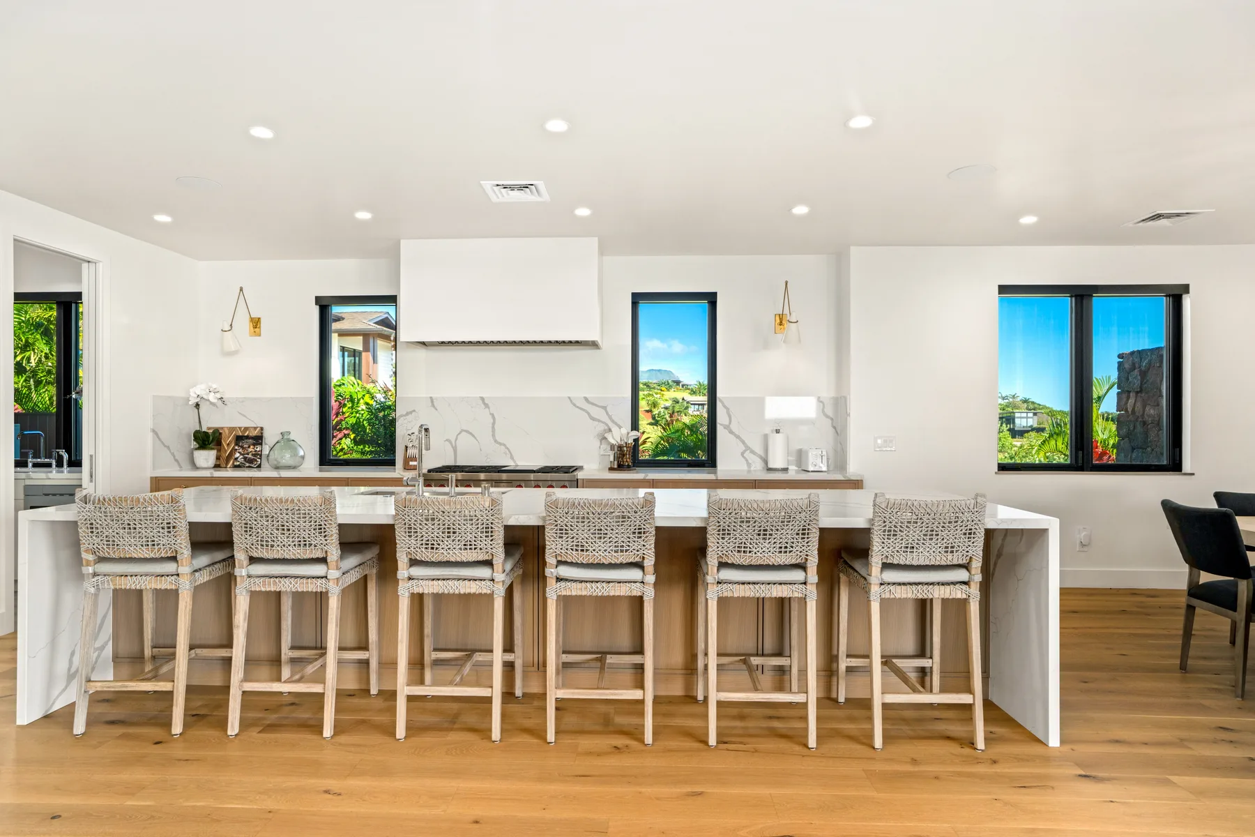 A bright kitchen with a long island and woven bar stools.