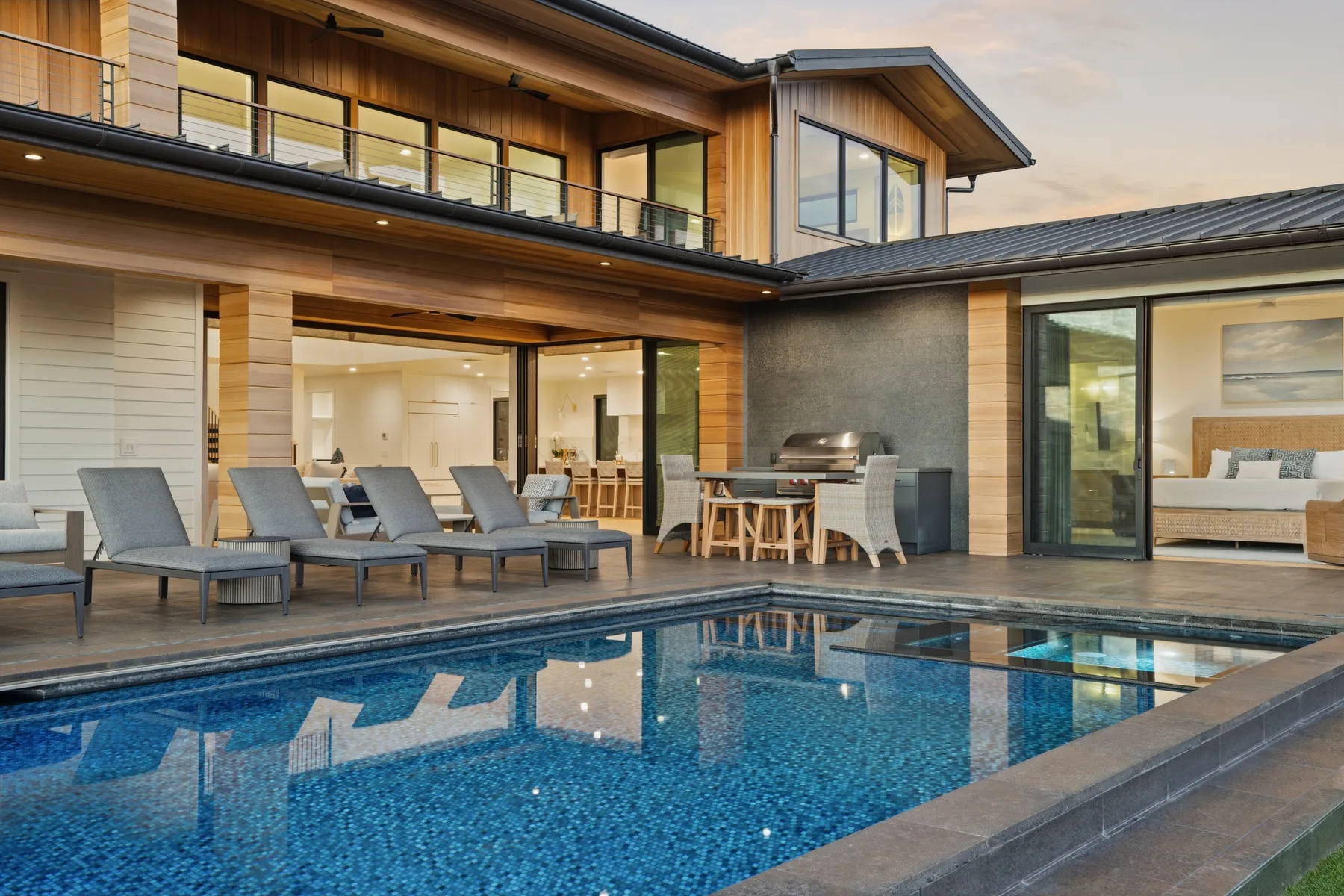 A modern house surrounds a swimming pool, with outdoor seating along the edge.