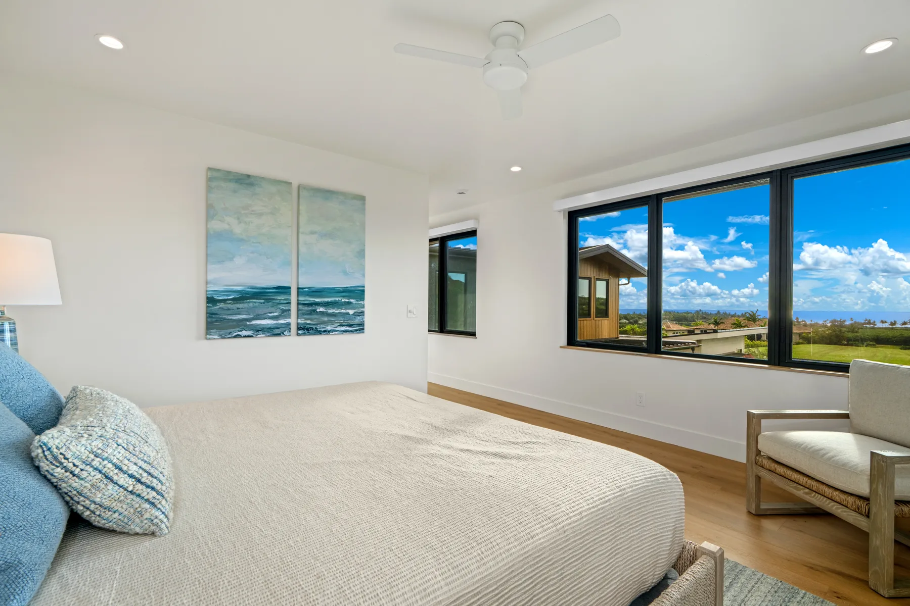A bright bedroom with a bed beside large windows overlooking the landscape.