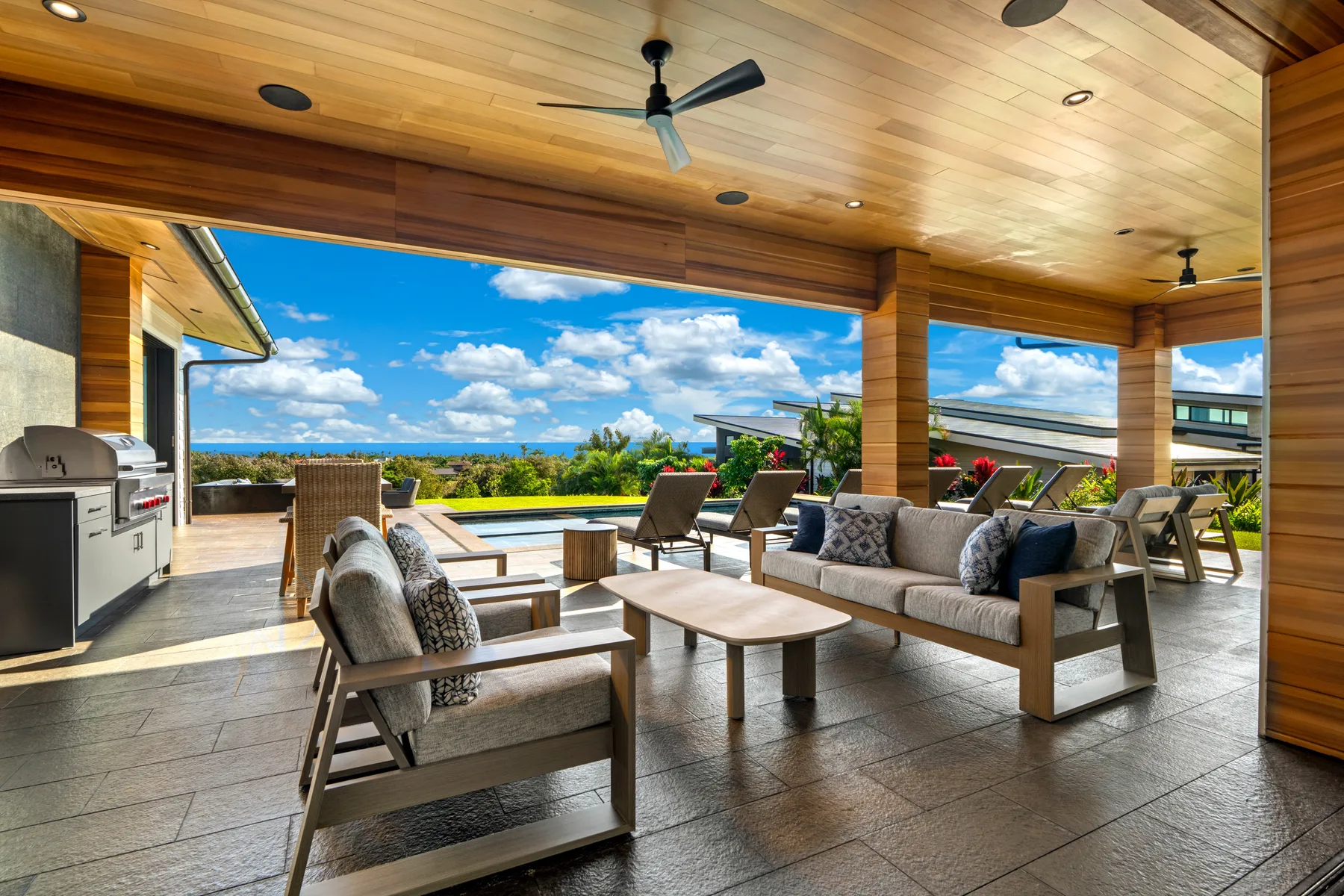 A covered outdoor seating area with a dining table and open views of the landscape.