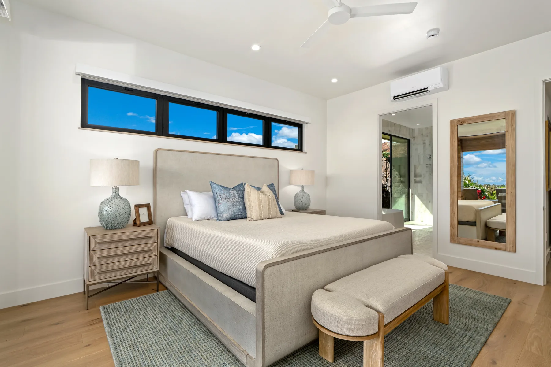 A bright bedroom with a large bed, bedside tables, and high windows.