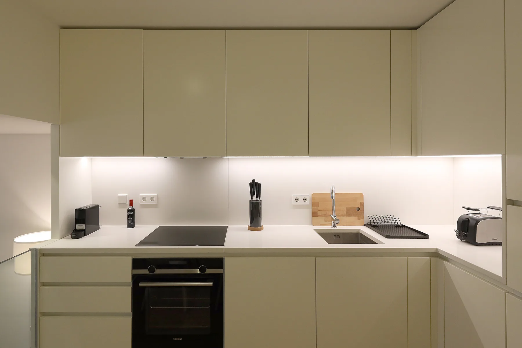 A modern kitchen with pale cabinets, a countertop, and built-in appliances.
