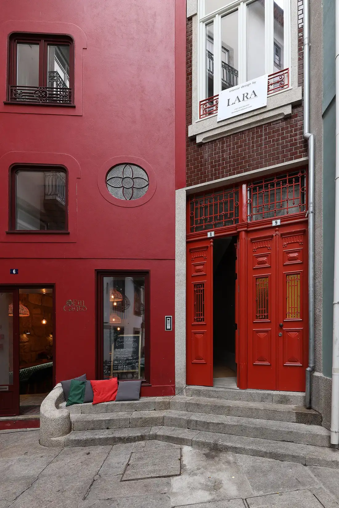 Street-facing building entrances include red doors and a curved stone bench.