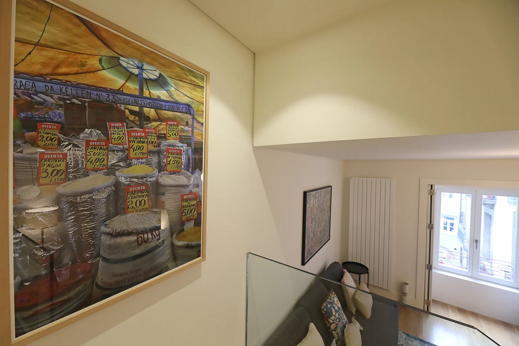 A stair landing overlooks a seating area and a bright window.