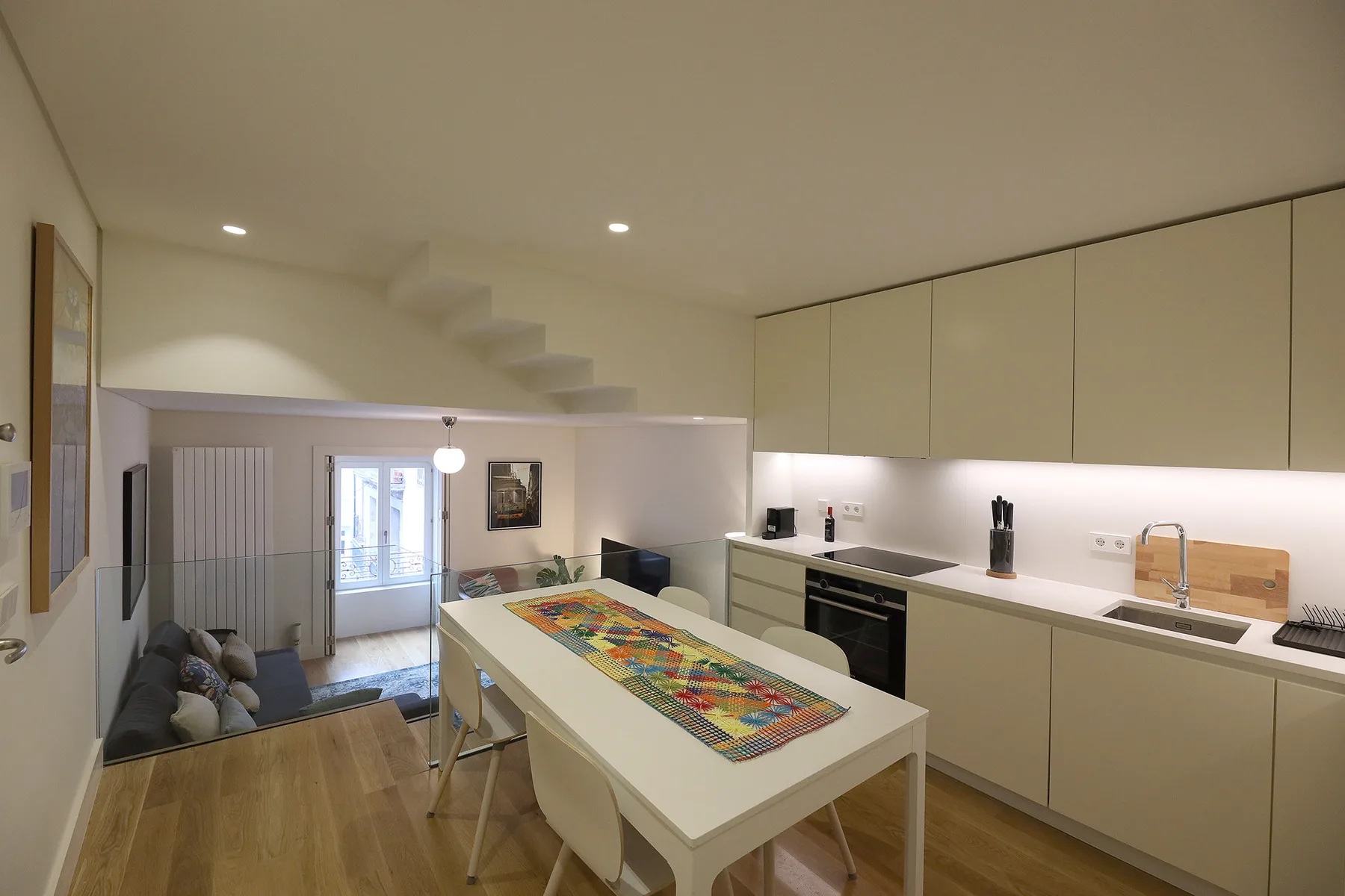 A bright kitchen and dining area with a long table and colorful runner.