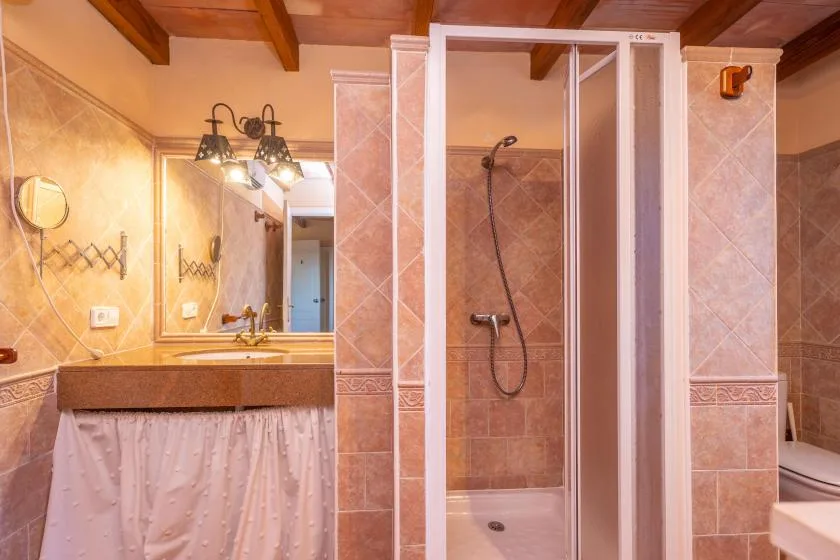 A tiled bathroom with a vanity, mirror, and glass shower.