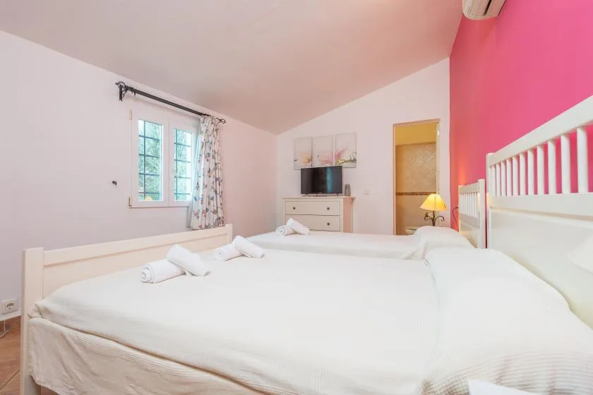 A bright bedroom with a large bed and a television on a dresser.