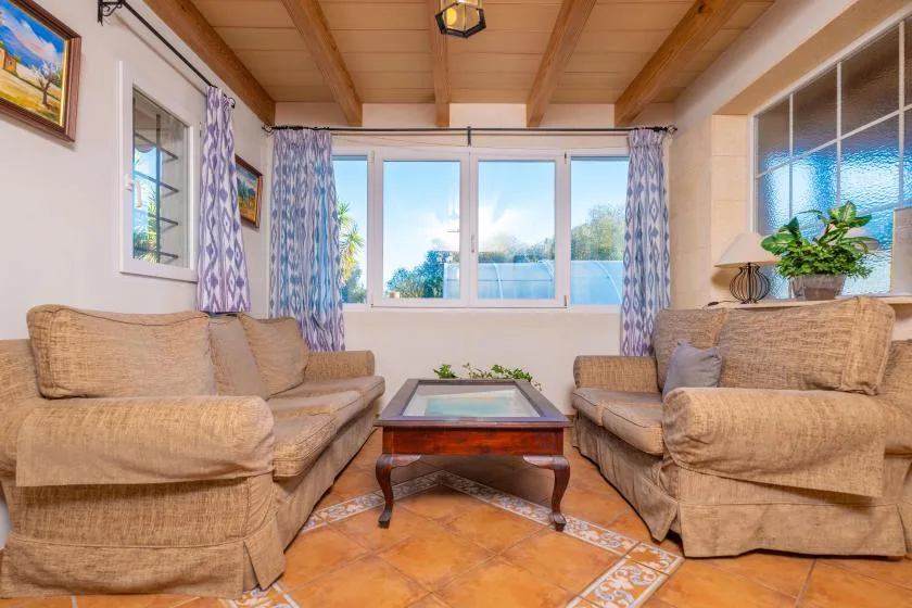 A living room with seating around a low coffee table and windows across the back.