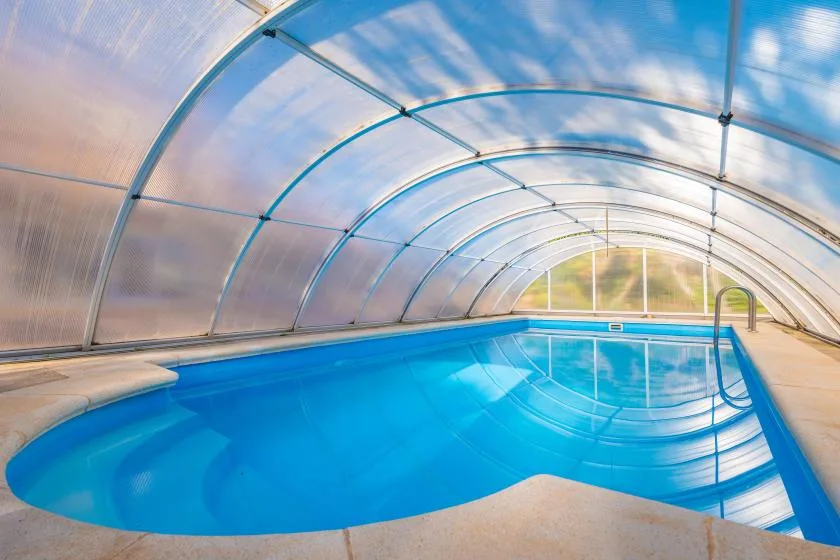 An indoor swimming pool sits beneath a curved translucent canopy.