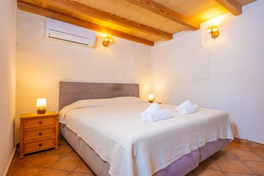 A bedroom with a neatly made bed and warm lighting.