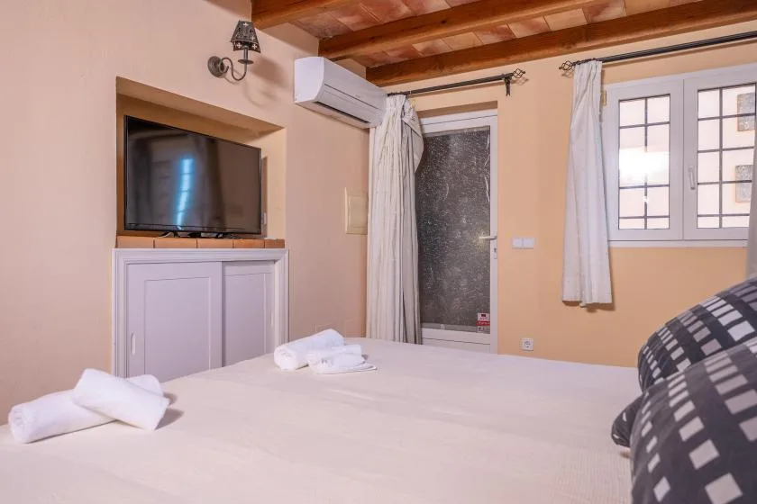 A bedroom with a bed, a television, and a window.