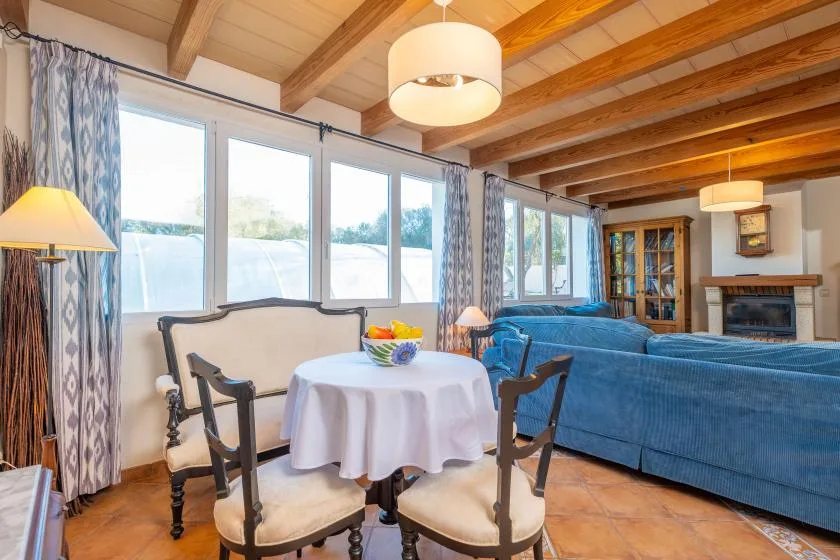 A living and dining area with blue seating beside large windows.