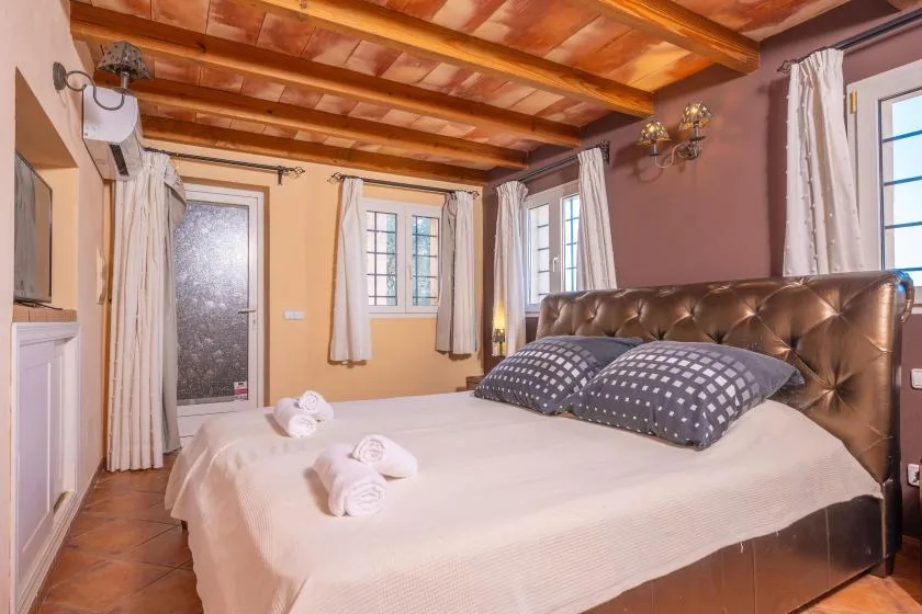 A bedroom with a large bed and several windows.