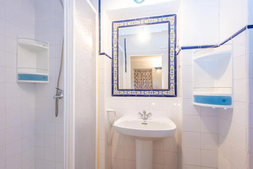 A tiled bathroom with a wall mirror above a sink.