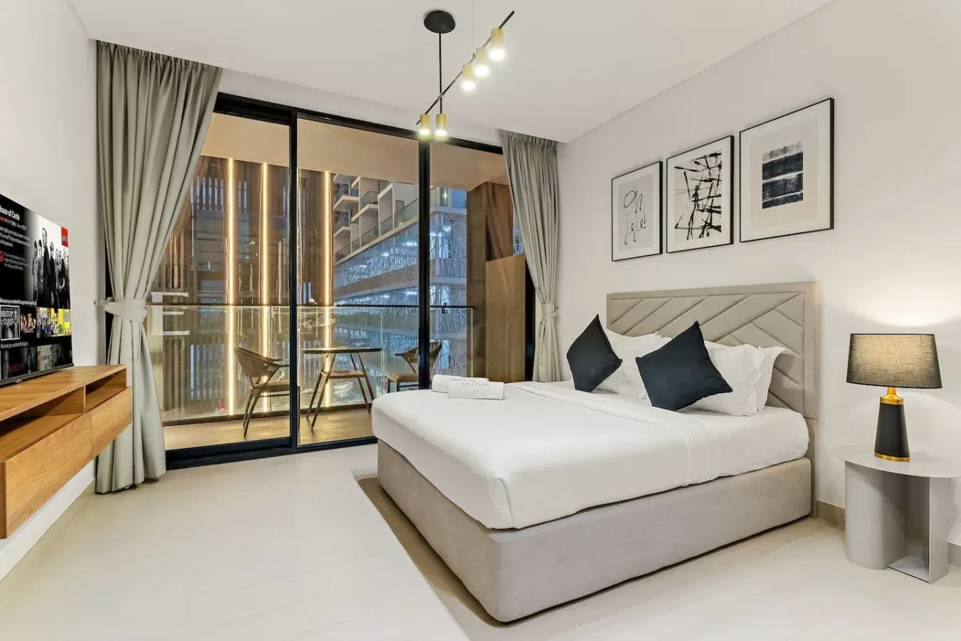 Un dormitorio con una cama tendida junto a ventanas de piso a techo y cortinas.