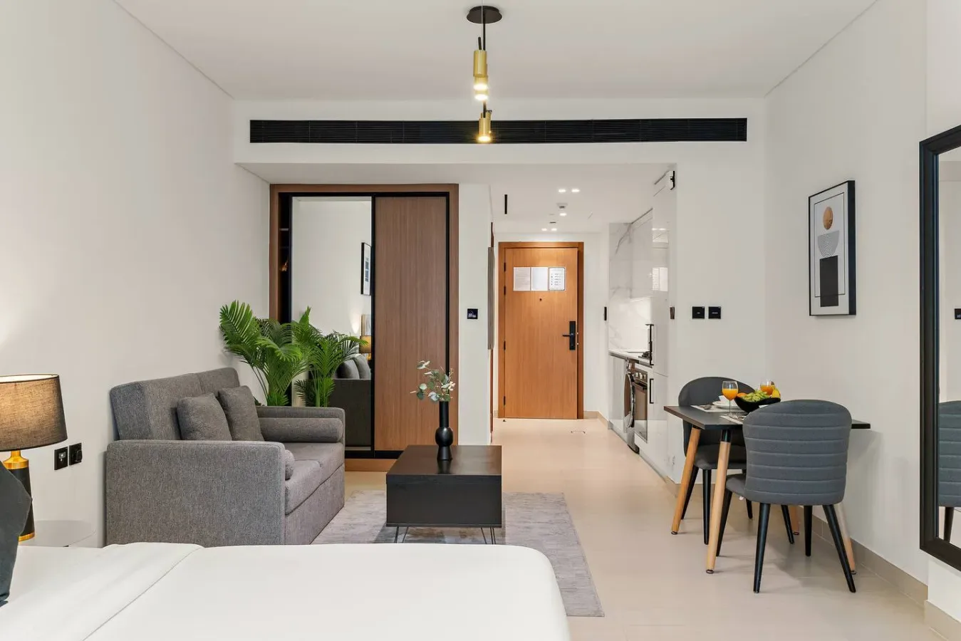 Una sala de estar y comedor moderna con asientos grises, una mesa y un pasillo.