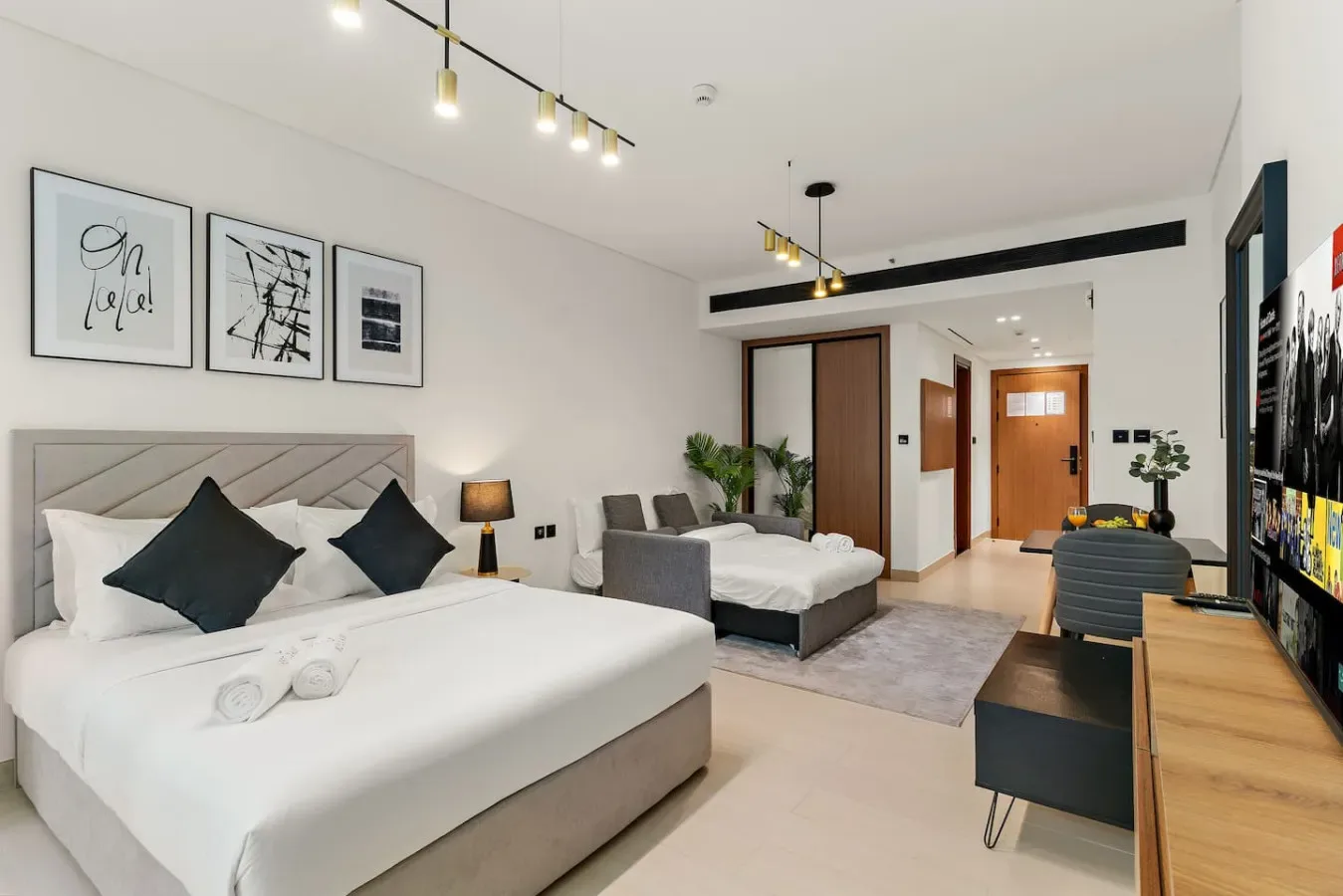 Un dormitorio luminoso con dos camas, cuadros en la pared y un televisor.