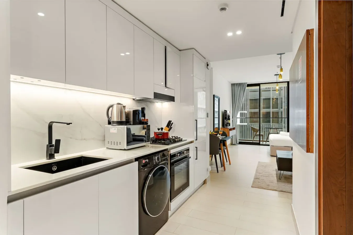 Una luminosa cocina abierta al salón, con una mesa de comedor cerca de las ventanas.