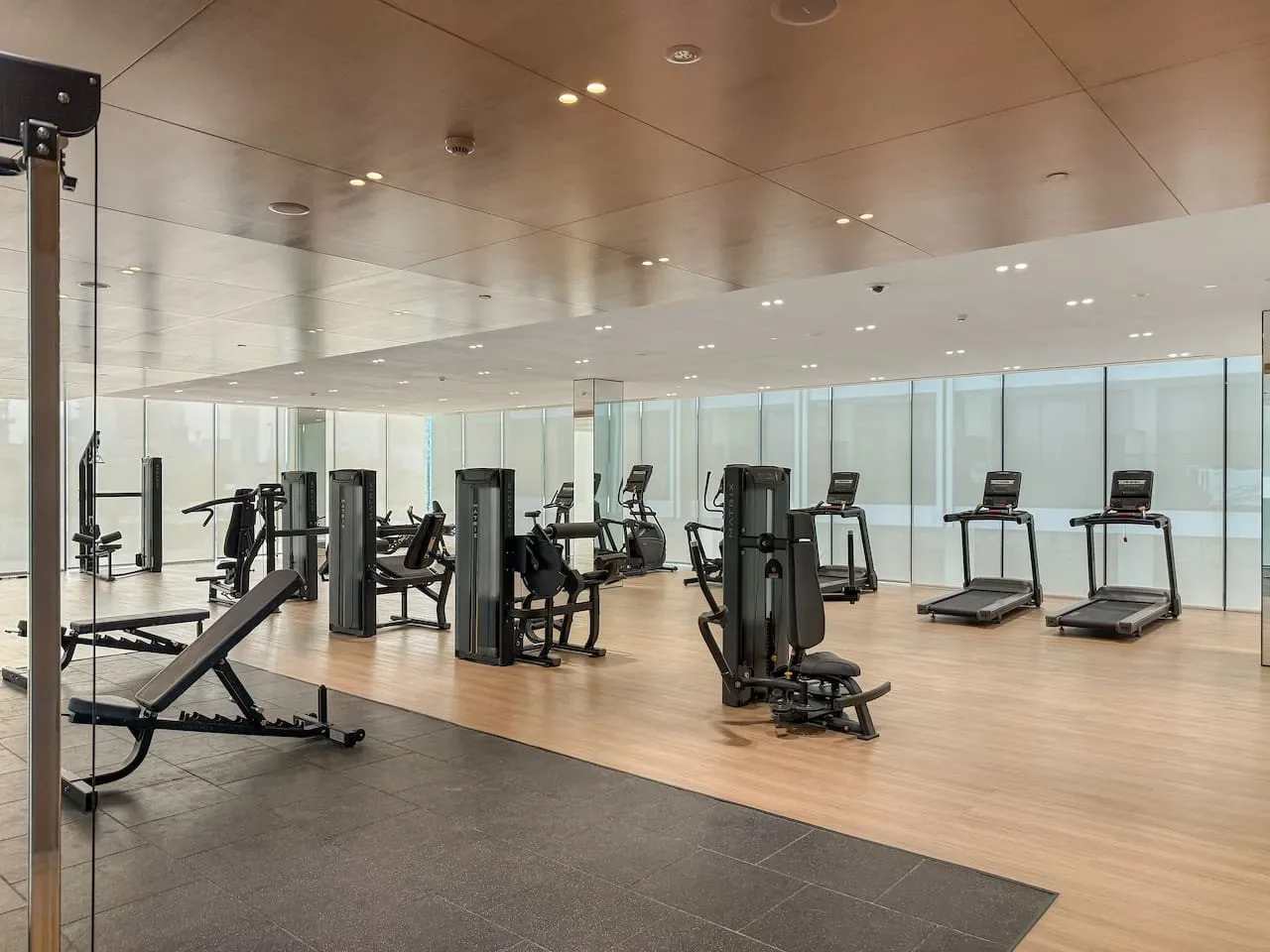 Una sala de ejercicio con espejos, máquinas y cintas de correr.